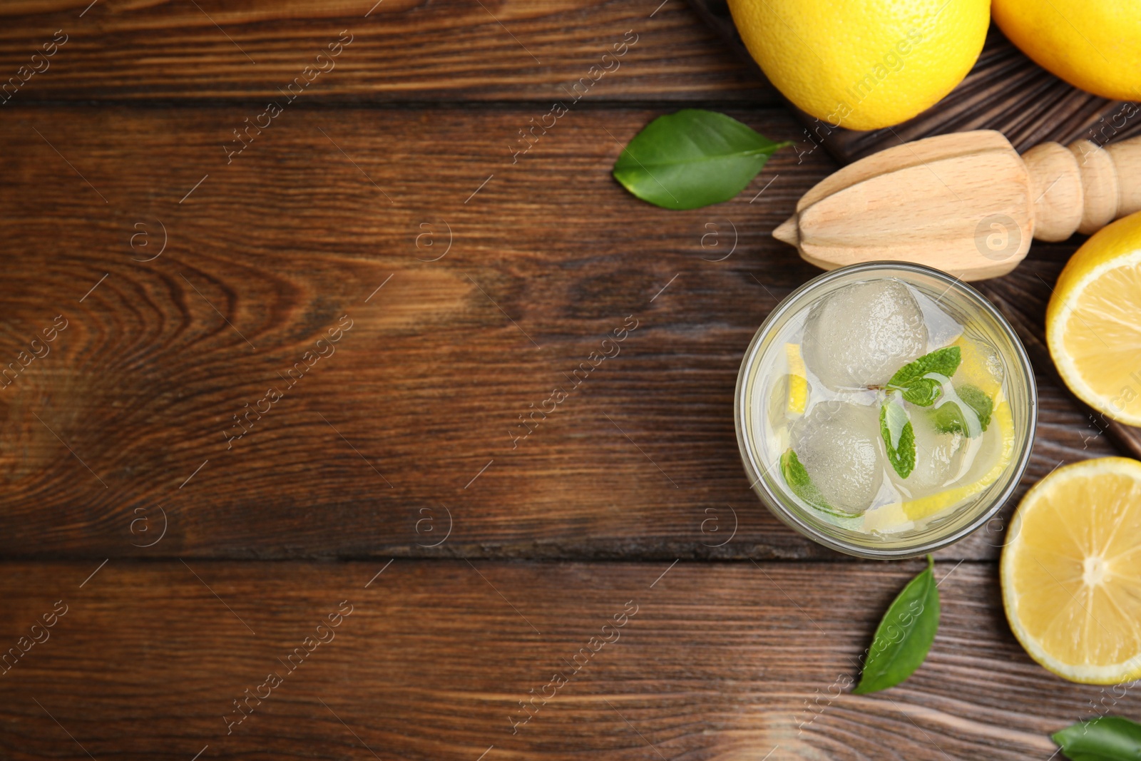 Photo of Cool freshly made lemonade, reamer and fruits on wooden table, flat lay. Space for text