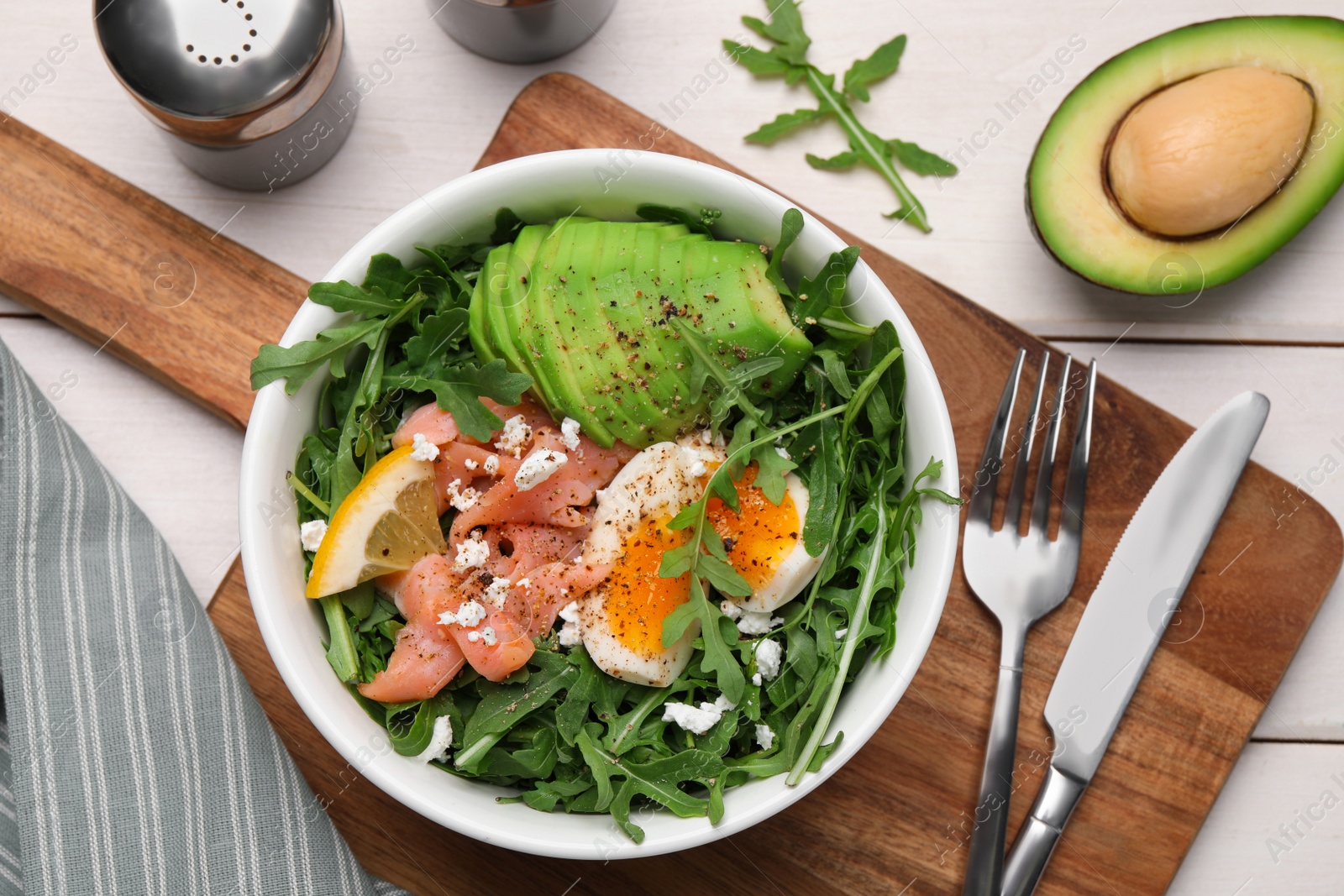 Photo of Delicious salad with boiled egg, salmon and avocado served on white wooden table, flat lay