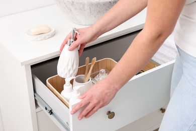 Bath accessories. Woman with container of cosmetic product indoors, closeup