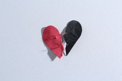 Halves of torn paper heart connected by thread on gray background, top view. Relationship problem concept