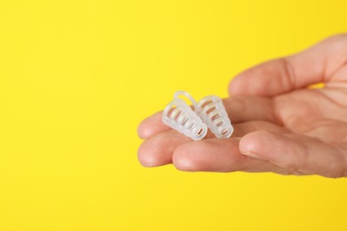 Photo of Woman holding anti-snoring device on yellow background, closeup. Space for text