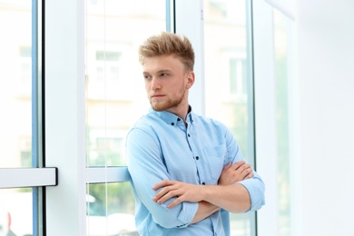 Photo of Portrait of handsome young man looking out window indoors