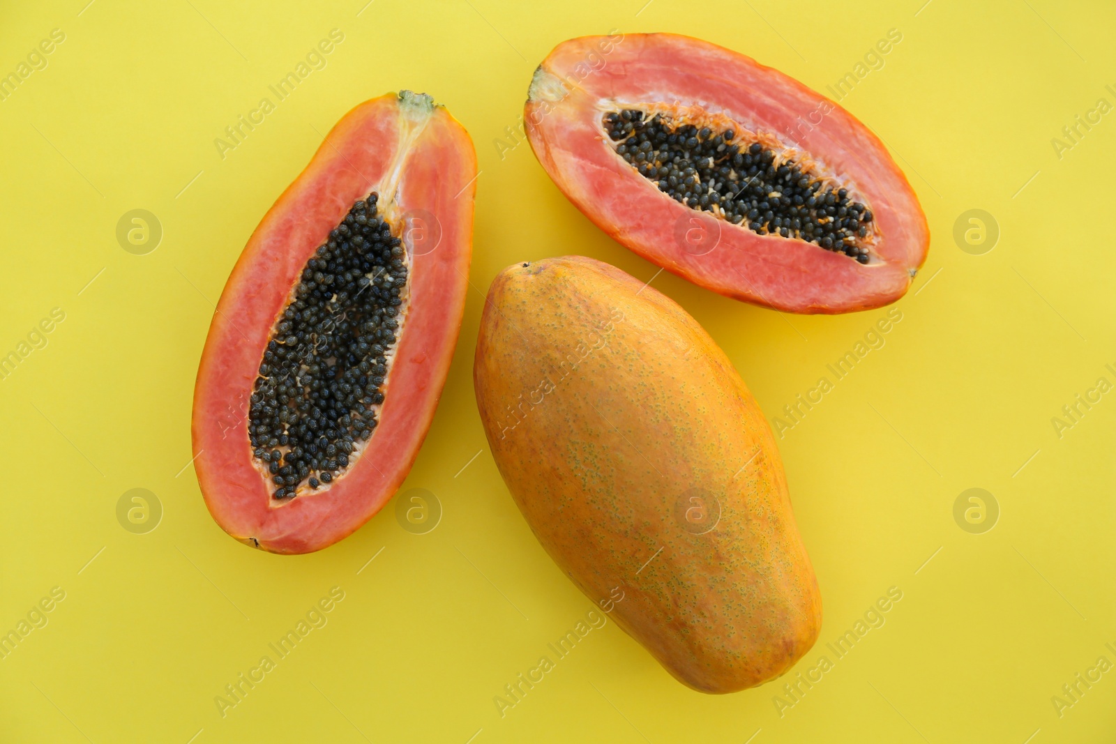 Photo of Fresh ripe cut and whole papaya fruits on light green background, flat lay