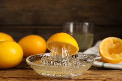 Squeezer with juice and lemons on wooden table