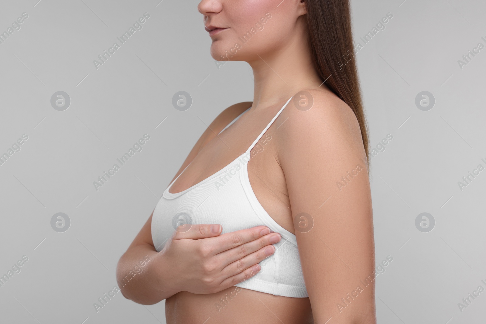 Photo of Mammology. Woman doing breast self-examination on light grey background, closeup