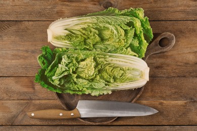 Photo of Halves of fresh ripe Chinese cabbage and knife on wooden table, flat lay