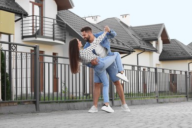 Happy couple dancing near house on city street