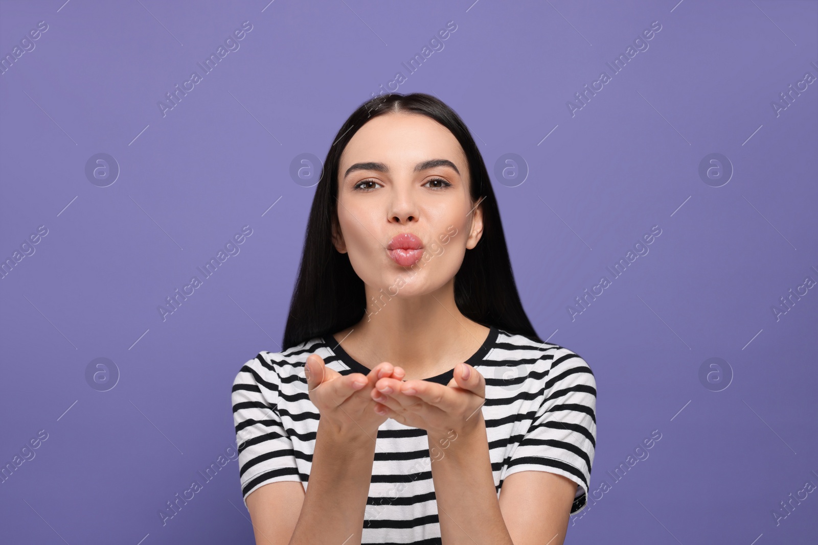 Photo of Beautiful young woman blowing kiss on purple background