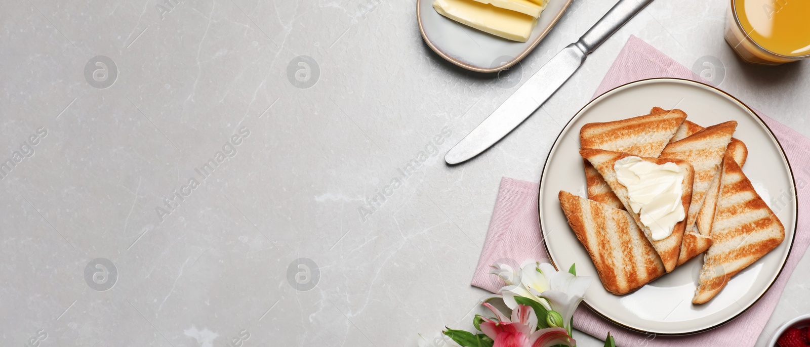 Image of Tasty toasts served with spreading butter and honey on light grey marble table, flat lay with space for text. Banner design