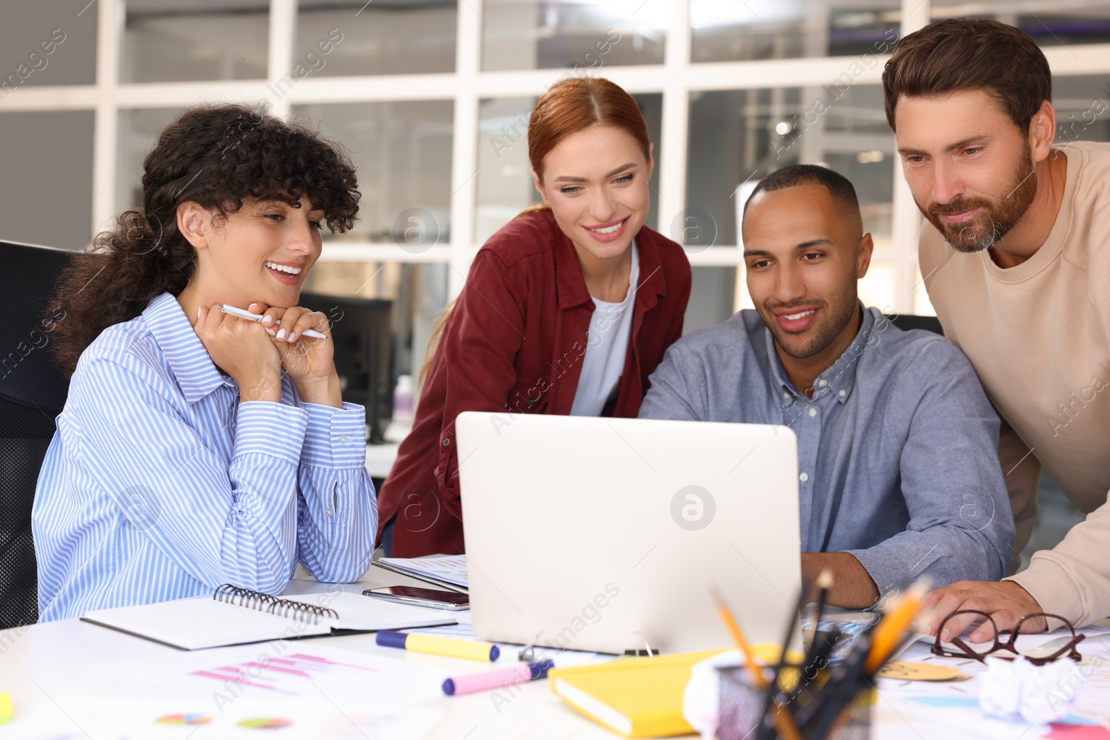 Photo of Team of employees working together at table in office. Startup project