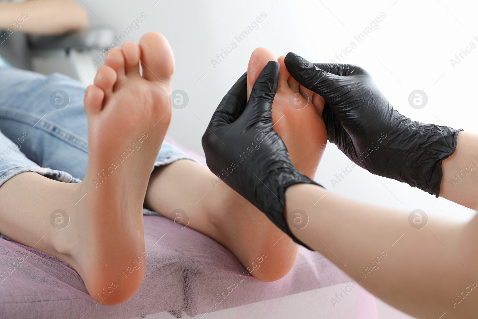 Photo of Professional master making foot massage to client in beauty salon, closeup. Preparation for pedicure procedure