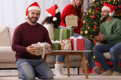 Photo of Christmas celebration in circle of friends. Happy man with gift box at home, selective focus