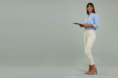Photo of Happy secretary with clipboard on light grey background. Space for text