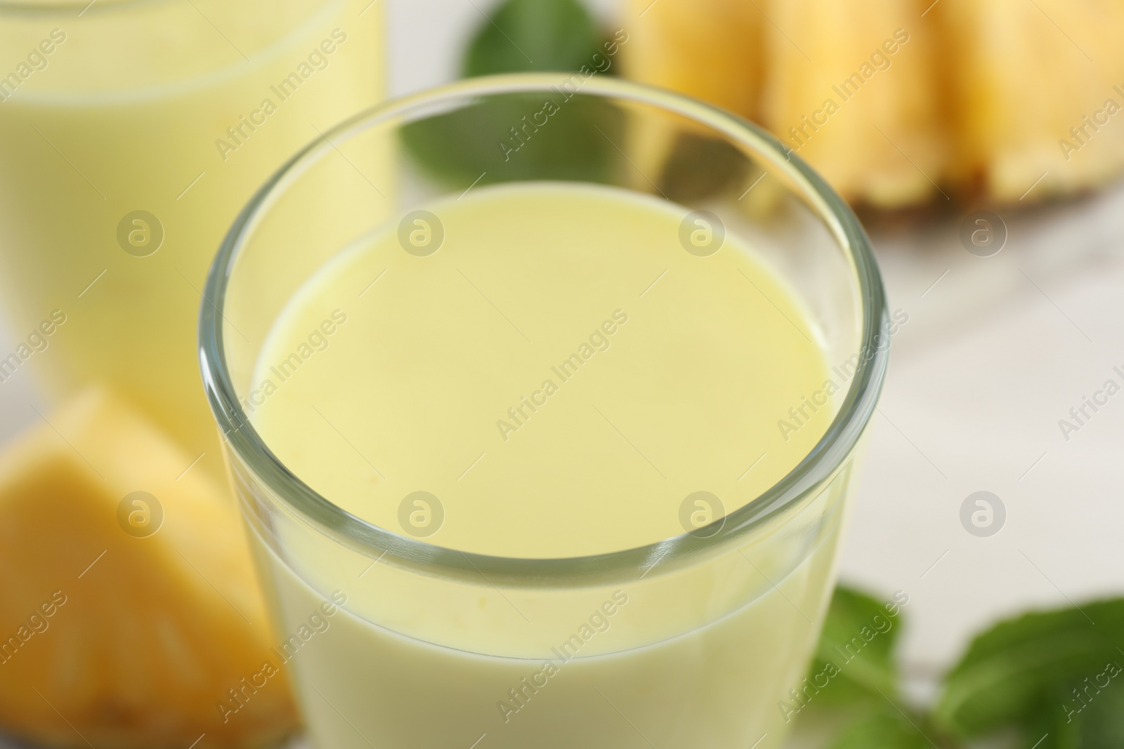 Photo of Tasty fresh pineapple smoothie on table, closeup