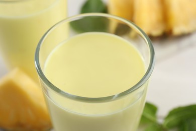 Photo of Tasty fresh pineapple smoothie on table, closeup