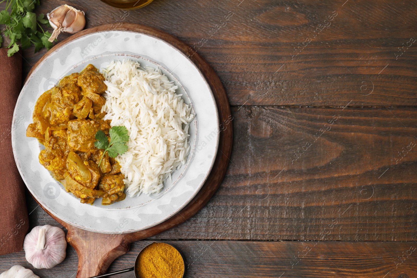 Photo of Delicious chicken curry with rice and ingredients on wooden table, flat lay. Space for text