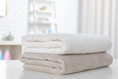 Stack of fresh towels on table in bathroom, closeup. Space for text