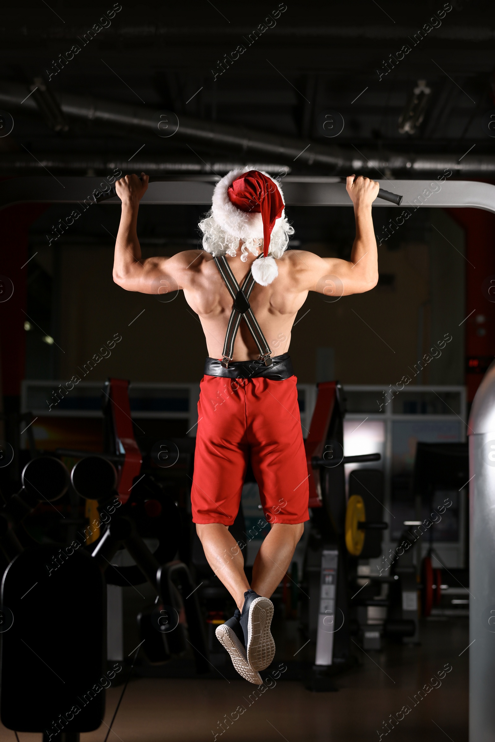 Photo of Young muscular man in Santa costume training at gym