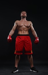 Photo of Man in boxing gloves on black background, low angle view