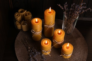 Photo of Beautiful burning beeswax candles and dried lavender flowers on table, above view