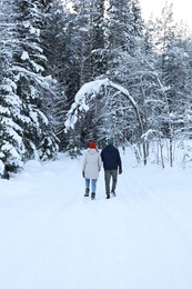 Photo of Couple walking near snowy forest, back view. Winter vacation