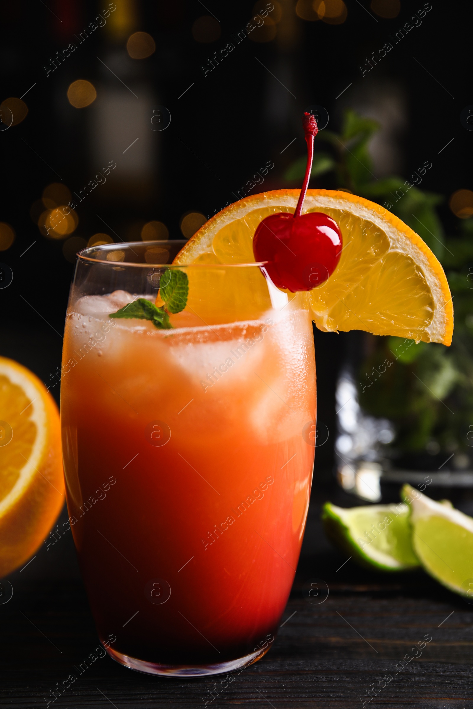 Photo of Fresh alcoholic Tequila Sunrise cocktail on black wooden table