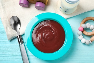 Flat lay composition with bowl of healthy baby food on light blue wooden table