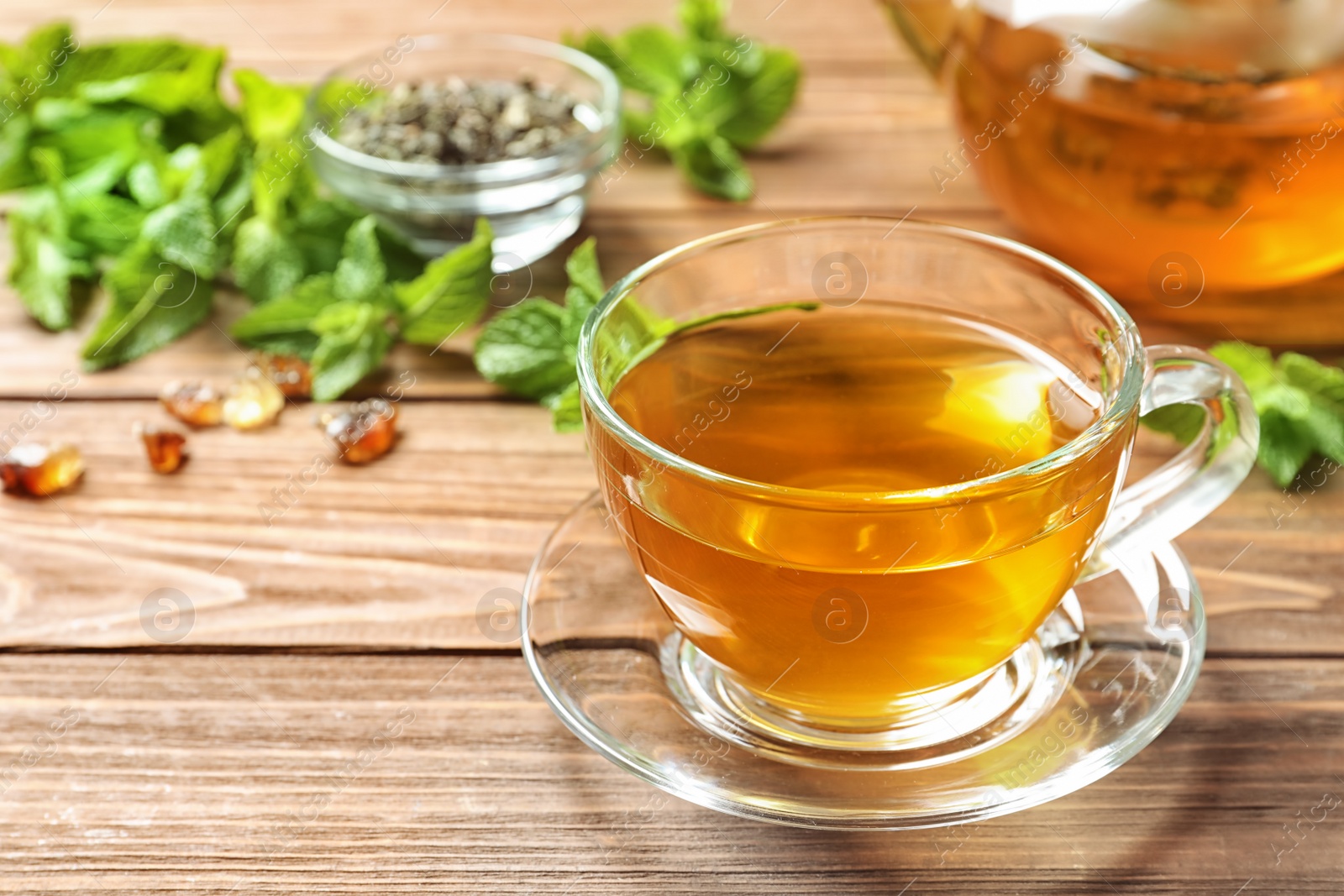 Photo of Cup with hot aromatic mint tea on wooden table