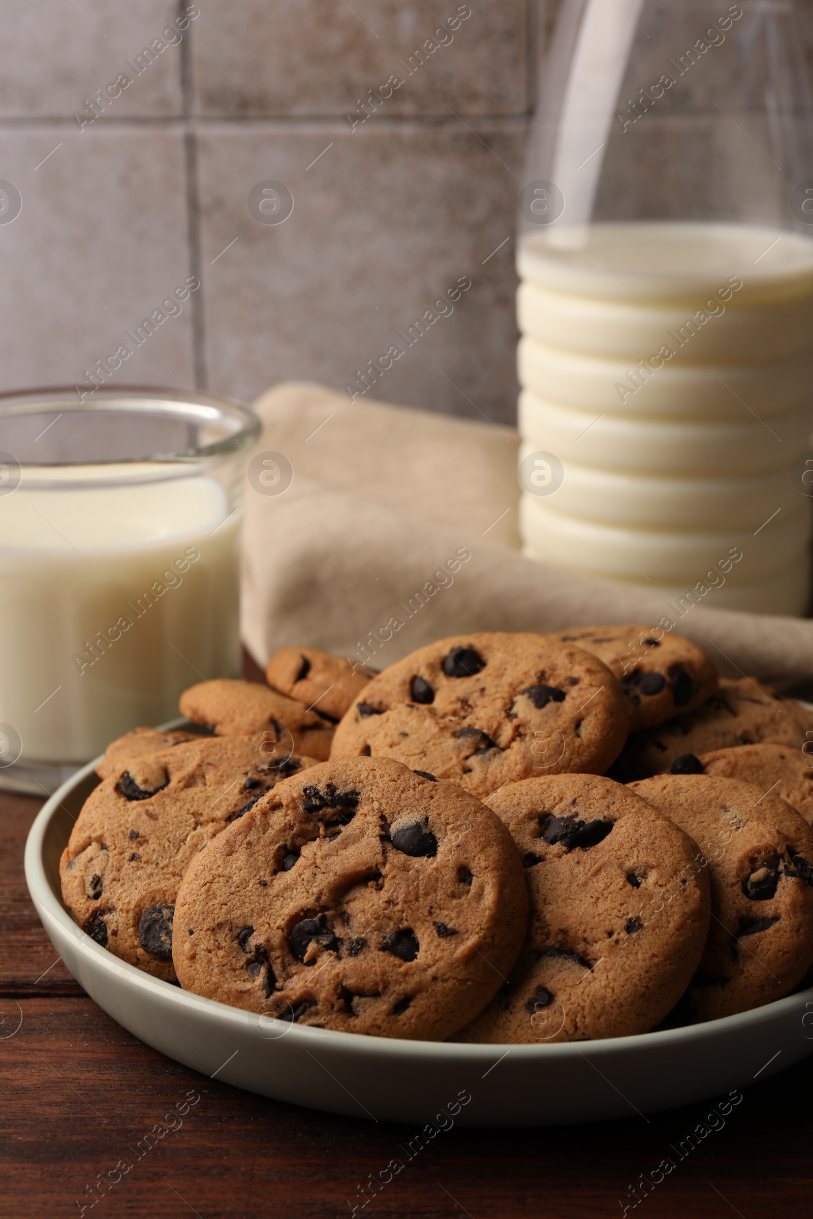 Photo of Delicious chocolate chip cookies and milk on wooden table, closeup