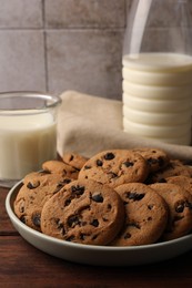 Delicious chocolate chip cookies and milk on wooden table, closeup