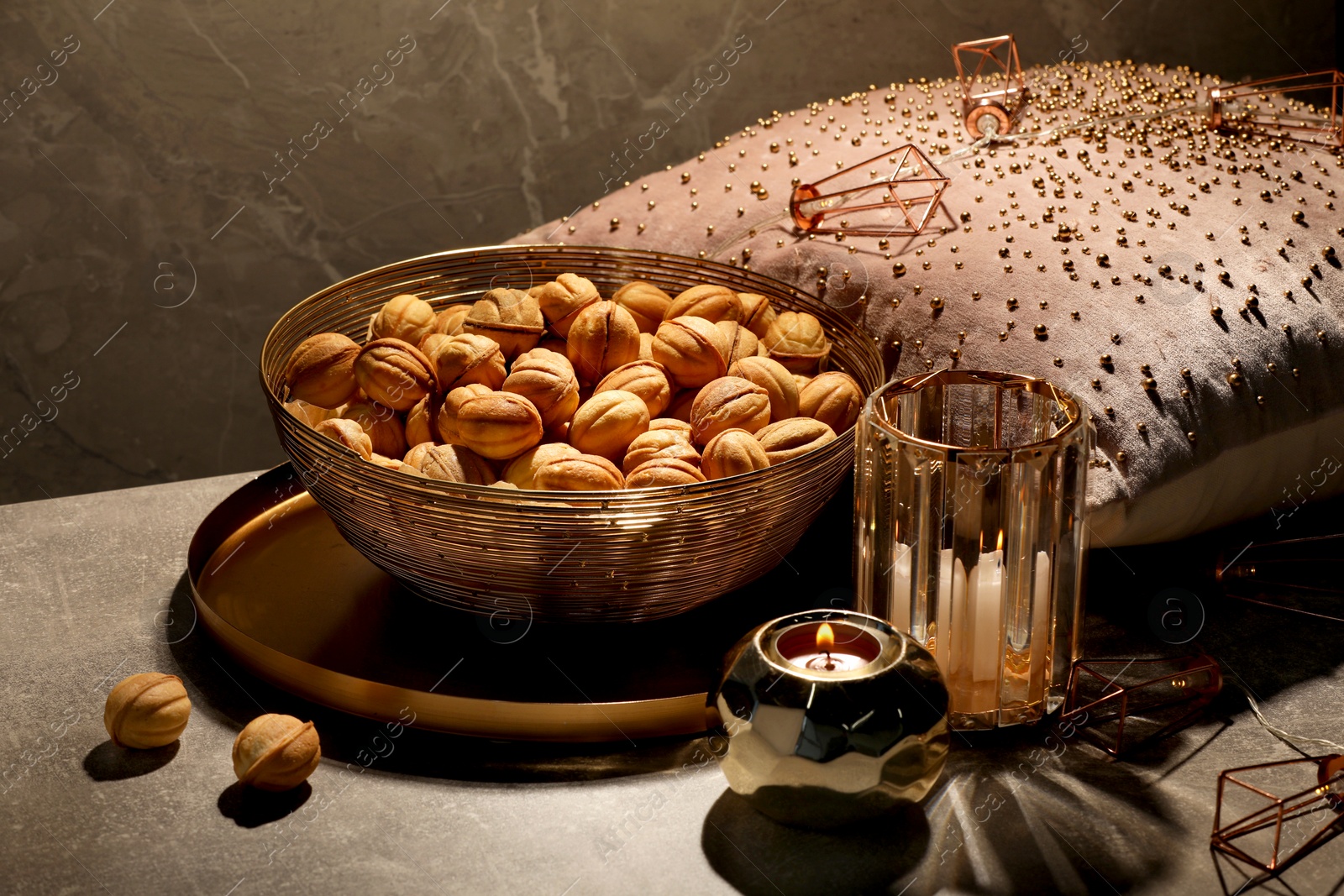 Photo of Delicious walnut shaped cookies, decor and burning candles on grey table, closeup. Tasty pastry carrying nostalgic home atmosphere