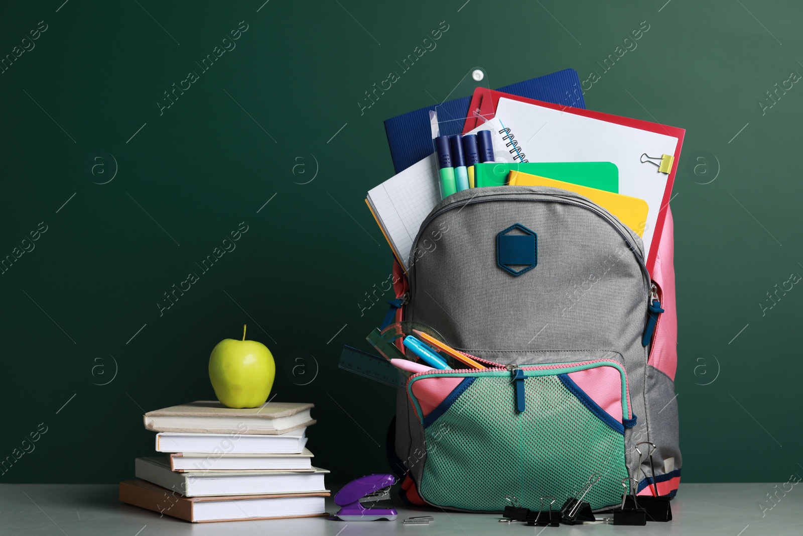 Photo of Backpack with different school stationery on white table near chalkboard