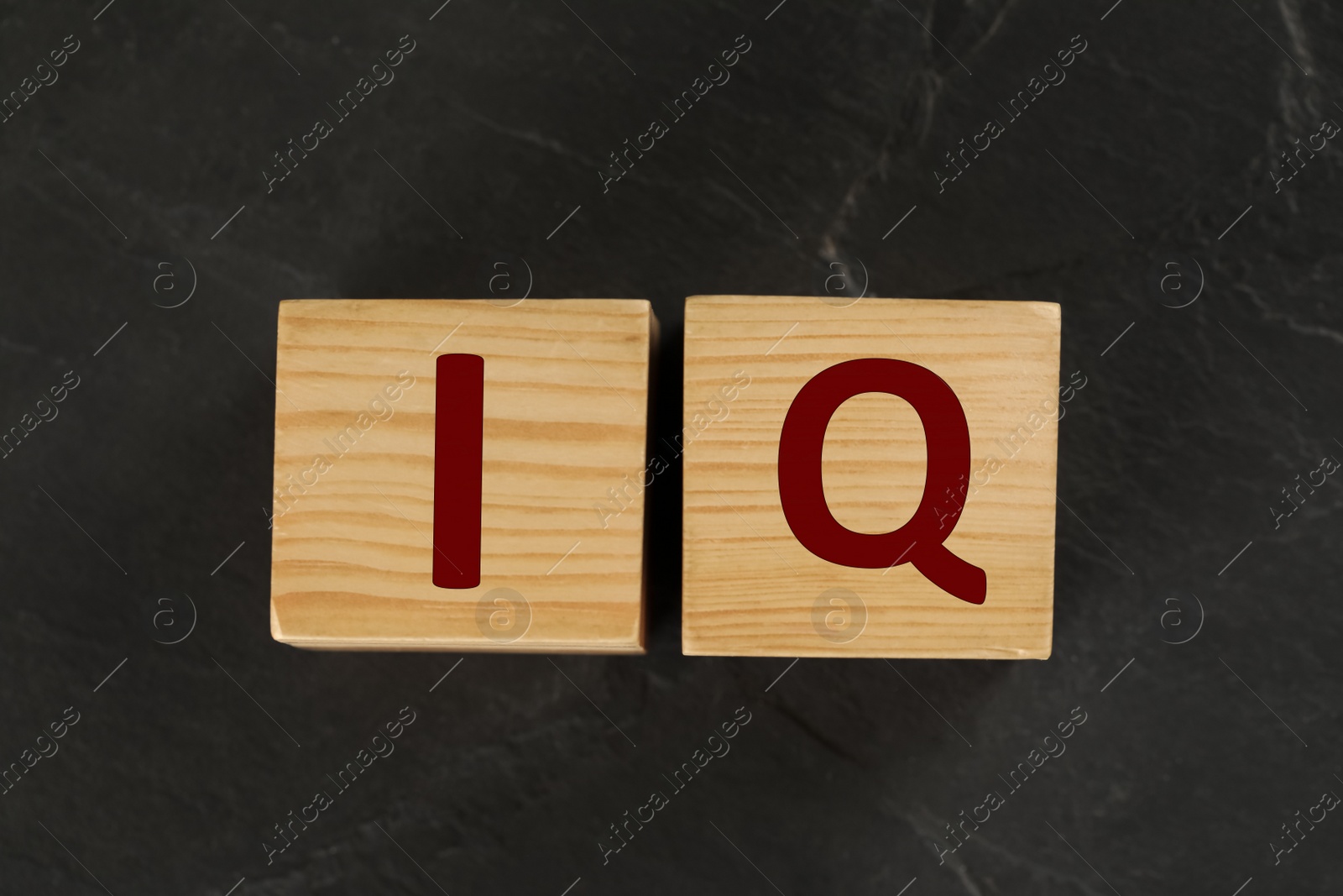 Photo of Wooden cubes with abbreviation IQ on black slate background, flat lay