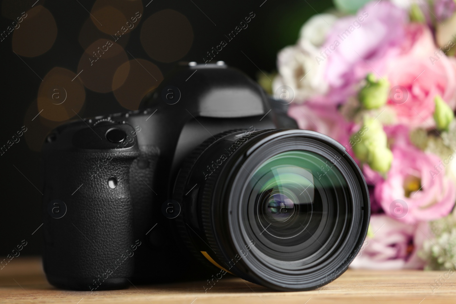 Photo of Modern camera and bouquet on wooden table. International Photographer's day