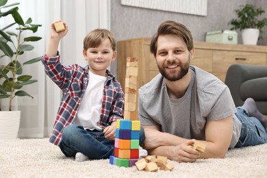 Photo of Family portrait of happy dad and son near tower of cubes at home