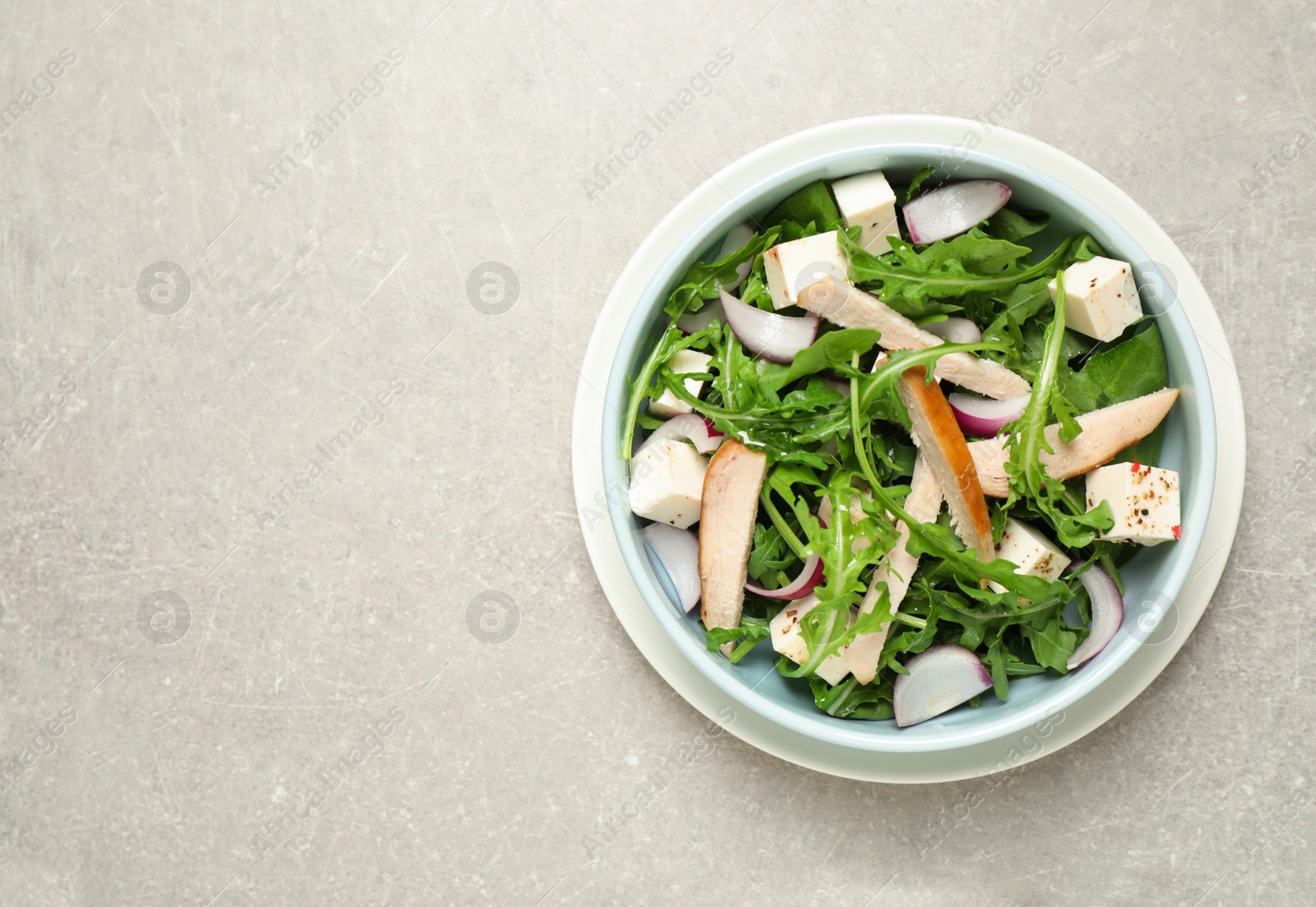 Photo of Delicious salad with chicken, arugula and feta cheese on grey table, top view. Space for text