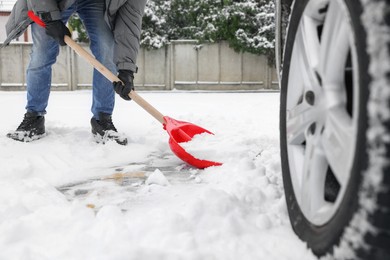 Photo of Man removing snow with shovel near car outdoors, closeup