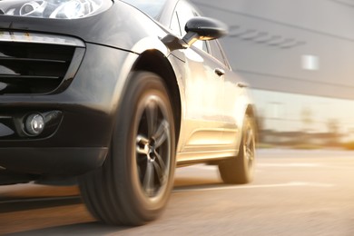 Image of Black car driving on road outdoors, closeup with motion blur effect. Space for text