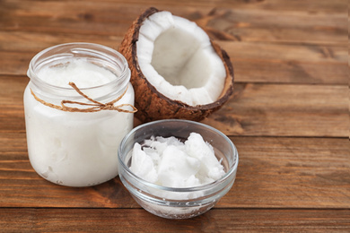 Half of ripe coconut and organic oil on wooden table. Healthy cooking