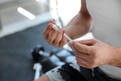 Photo of Sportsman with syringe in gym, closeup. Doping concept