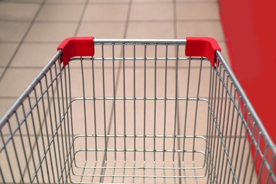 Photo of Empty metal shopping cart in supermarket, closeup