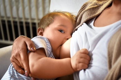 Photo of Woman breast feeding her baby at home, closeup