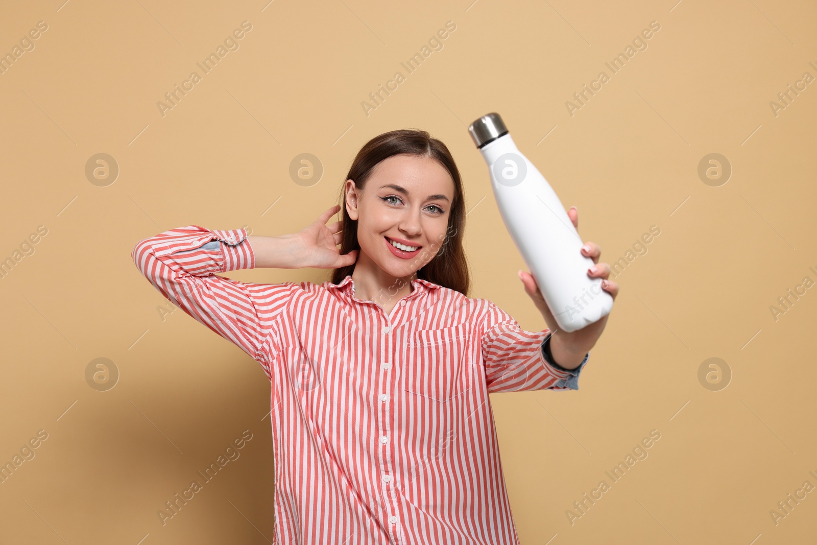 Photo of Beautiful young woman with thermos bottle on beige background