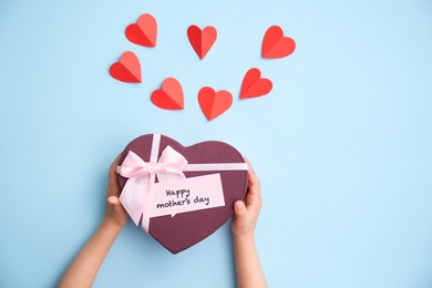 Photo of Child holding gift box for Mother's Day on color background