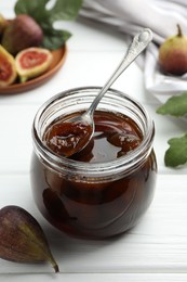 Photo of Jar of tasty sweet jam and fresh figs on white wooden table