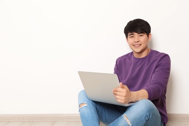Photo of Man in casual clothes with laptop near light wall