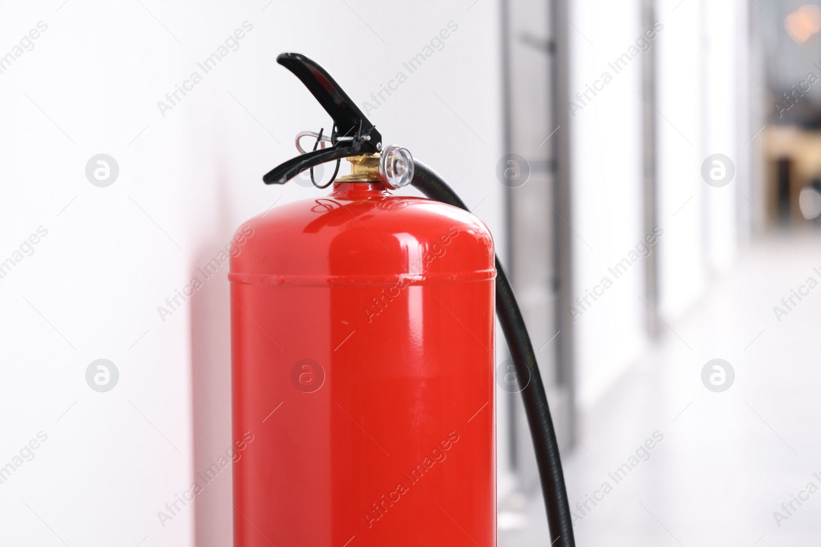 Photo of One red fire extinguisher in hall, closeup