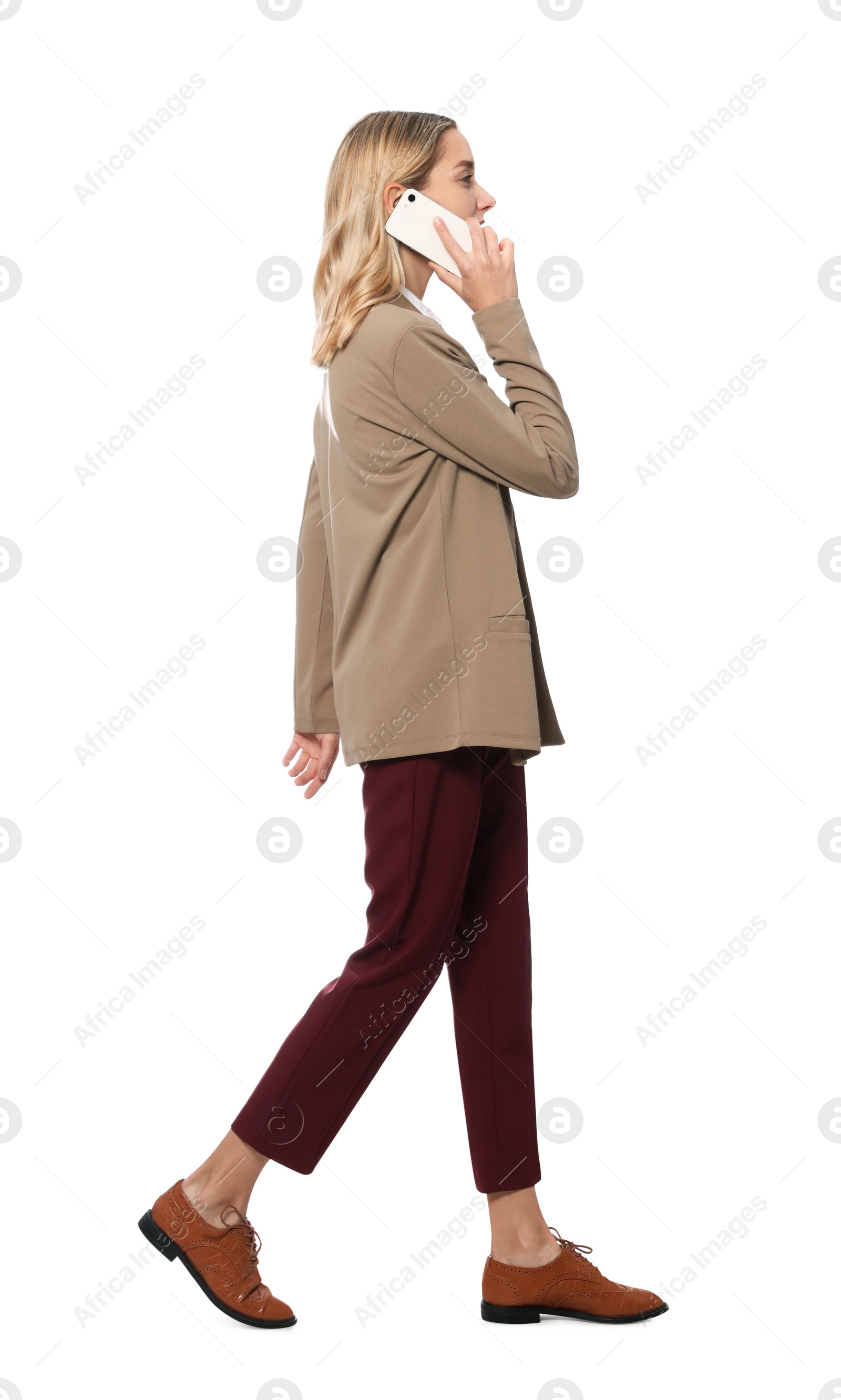 Photo of Young woman talking on smartphone and walking against white background