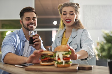 Photo of Happy young couple having lunch in burger restaurant