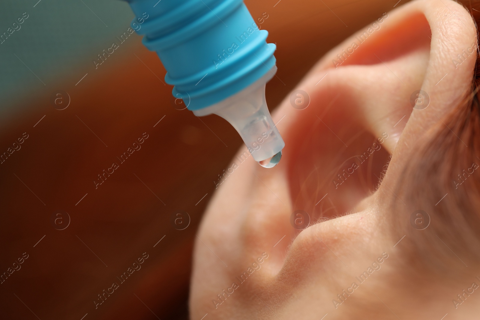 Photo of Woman applying medical ear drops, macro view